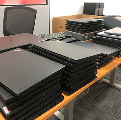 Laptops stacked on a desk ready to be donated to TCC Computer Club 